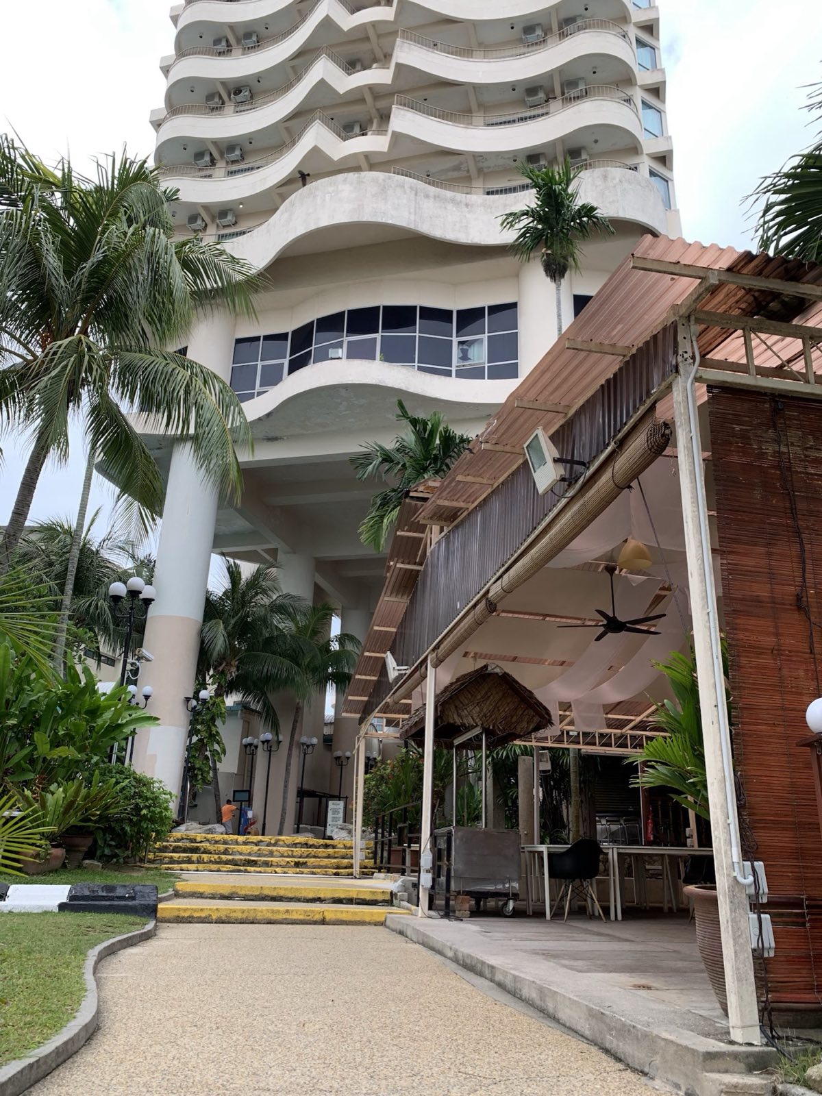 The base of the resort tower with a beach cabana and a path lined with palms