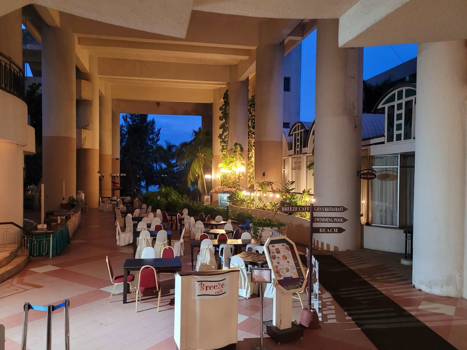 Breeze Café open-air beachfront dining under the resort's columns at dusk