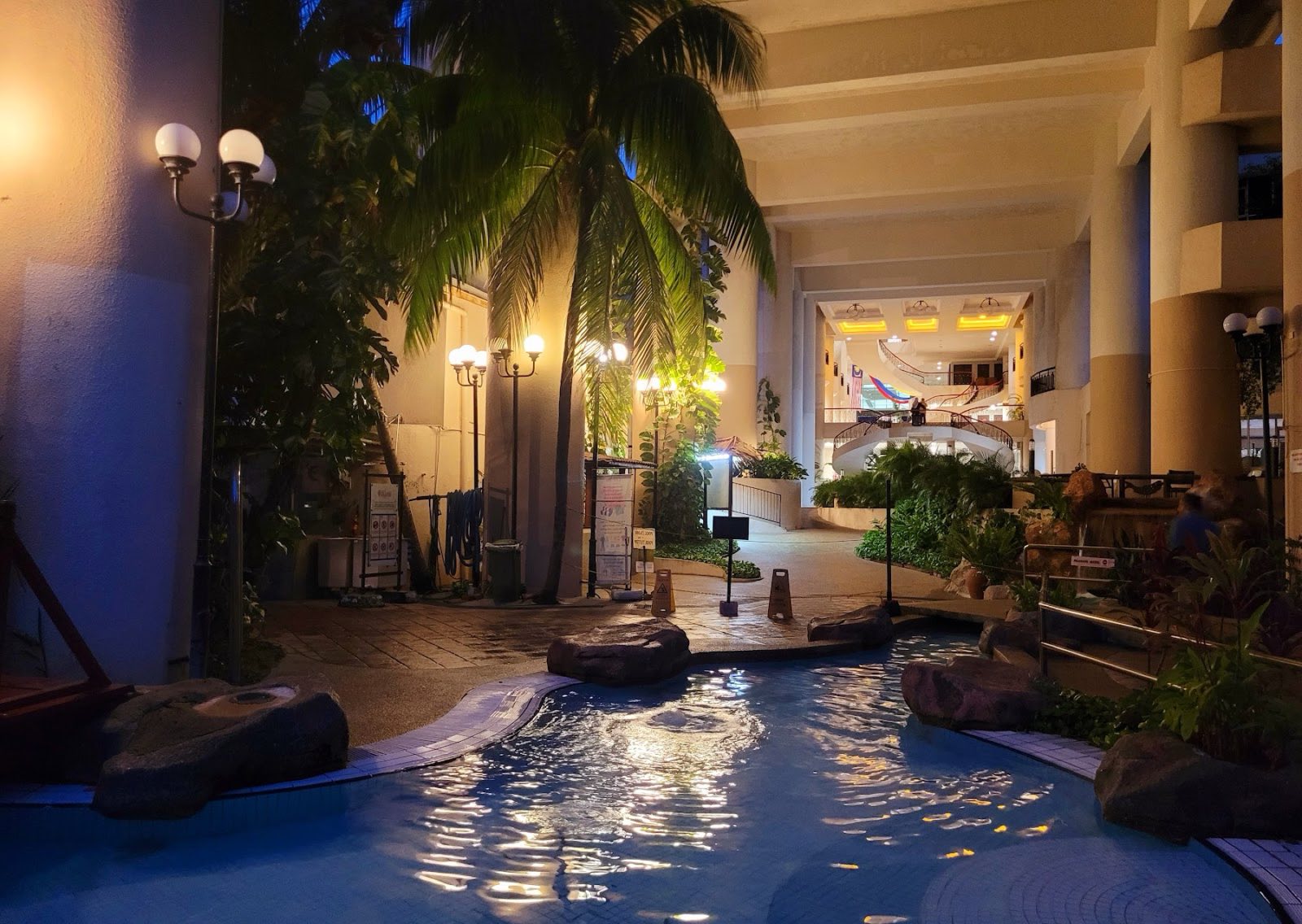 The lagoon pool lit warmly at night, palms reflected in the water