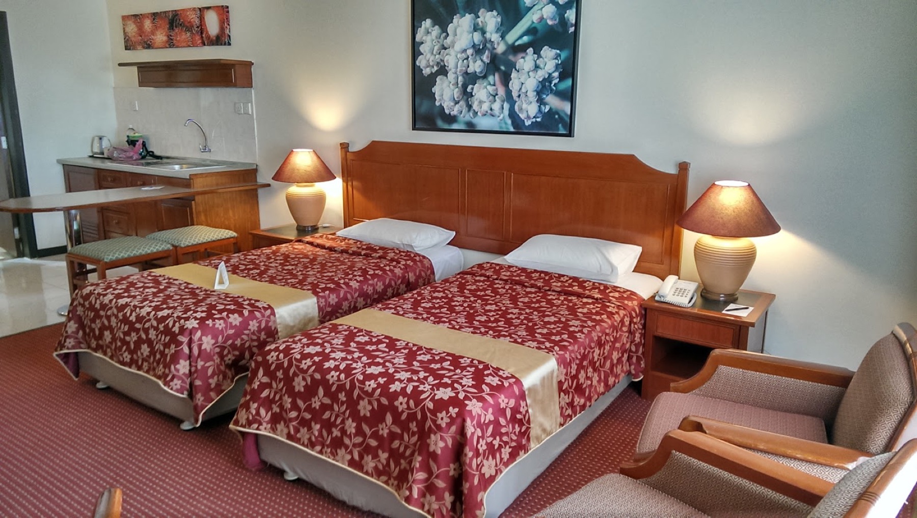 A spacious sea-view twin room at Rainbow Paradise with twin beds, a tea-and-coffee station and lounge chairs